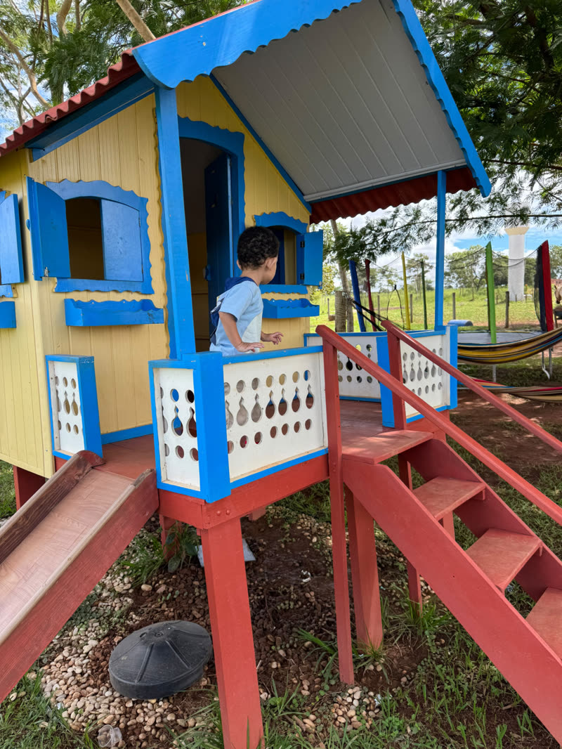 Criança na casinha de brinquedo da área infantil ao ar livre