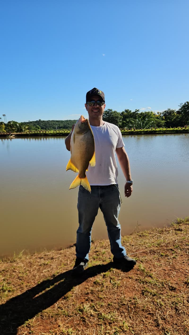 Pescador mostrando o peixe fisgado no lago